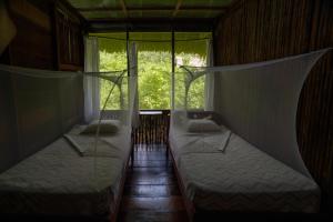 two beds in a room with a window at Amak Iquitos Ecolodge - All Inclusive in Santa Clara