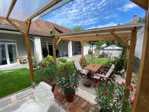 eine Terrasse mit einer hölzernen Pergola sowie einem Tisch und Stühlen in der Unterkunft Bonne Vie Cottage - Zebegény in Zebegény