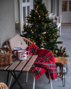 een kerstboom en een tafel met mokken en een deken bij Bonne Vie Cottage - Zebegény in Zebegény