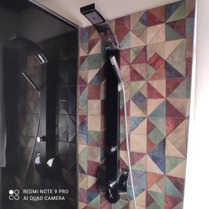 La salle de bains est pourvue d'une douche et d'un mur carrelé coloré. dans l'établissement Johnny's loft, à Agrinion