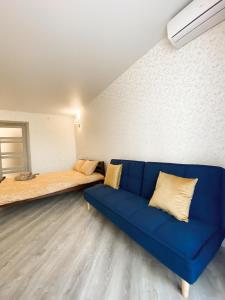 een woonkamer met een blauwe bank en een bed bij Стильні апартаменти в самому Центрі біля Корпусного саду - Мережа HELEN in Poltava