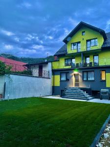 une maison jaune avec une pelouse devant elle dans l'établissement Willa Barwy Wspomnień, à Muszyna