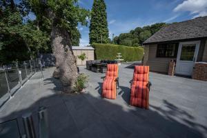 two orange chairs sitting on a sidewalk next to a tree at The Larches in Bewdley