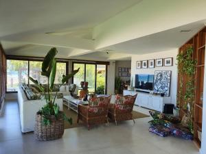 a living room with a couch and chairs and a tv at Pé na areia Beach House in Camaçari