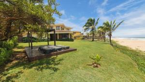 a house on the beach with a grass yard at Pé na areia Beach House in Camaçari
