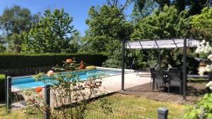a swimming pool with a pergola next to a yard at Gîte de charme en Dordogne avec Piscine et jardin in Jumilhac-le-Grand
