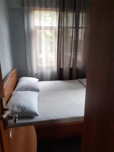 Bett mit weißer Bettwäsche und Kissen vor einem Fenster in der Unterkunft это квартира где сдаётся только одна комната с проживанием владельца квартиры на одной площади in Istanbul