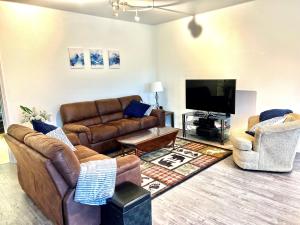 a living room with couches and a flat screen tv at Newly Remodeled spacious units, minutes from mountains, inlet, downtown and airport in Anchorage
