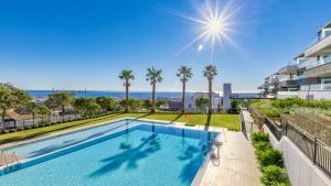een zwembad met palmbomen en de oceaan op de achtergrond bij Estepona Luxury Apartment in Estepona