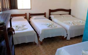 Habitación con 3 camas y sábanas blancas. en Pousada Ilha do Desejo en Olivença