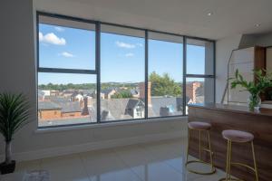 Habitación con ventanas grandes con taburetes frente a un bar en Rooftop Apartment At Queens Beautiful views, en Belfast