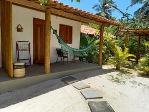 een patio van een huis met een hangmat bij Recanto Verde - Praia de Santo Antônio in Diogo