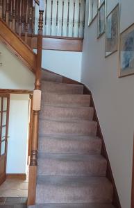 a staircase in a house with wooden railings at Woodpeckers Cottage B&B in Pett