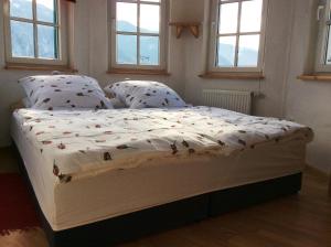 a bed in a small room with windows at Ferienwohnung Rosenlehner in Kiefersfelden