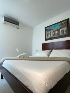 a bedroom with a large white bed with a picture on the wall at Villalba Boutique Hotel in Valledupar