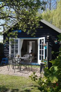 un cottage nero con tavolo e sedie su un patio di Hortensia Eiland a Zegveld
