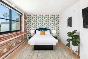 1 dormitorio con cama y pared de ladrillo en The Brick Boutique Hotel, en Oceanside