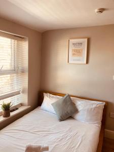 um quarto com uma cama com lençóis brancos e uma janela em 'Bloomfield' at stayBOOM em Lancaster