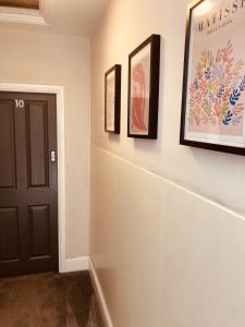 a hallway with three pictures on the wall and a black door at 'Bloomfield' at stayBOOM in Lancaster