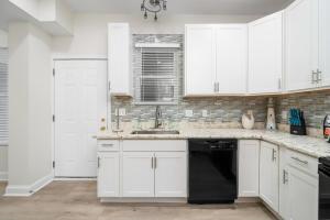 a kitchen with white cabinets and a black dishwasher at The Palace On Wisconsin A 4bedroom Luxury Home in Columbus