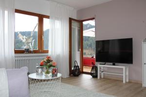 a living room with a television and a table with flowers at Waldblick in Baiersbronn