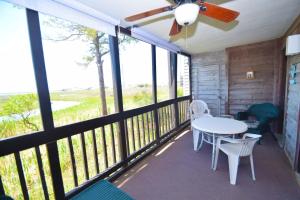 a screened porch with a table and chairs and a ceiling fan at Our Place At The Beach 105E Condo in Ocean City