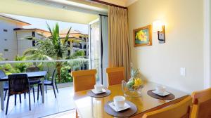 a dining room with a table and chairs and a balcony at Honua Kai - Hokulani 414 in Lahaina