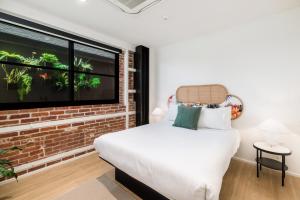 a bedroom with a brick wall and a bed and a window at The Brick Boutique Hotel in Oceanside
