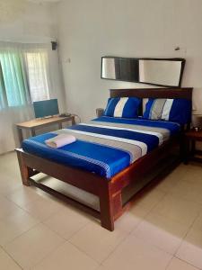 una camera da letto con un grande letto con lenzuola blu e bianche di Queen Zee Garden Apartments a Kololi
