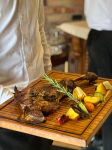 a person holding a plate of meat and vegetables at PalmaNova Resort in Tirana