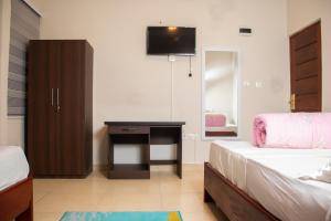 a bedroom with two beds and a desk with a television at El-King Home Lodge in Afwerasi