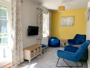 a living room with two blue chairs and a tv at Park View Annexe 