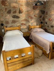 2 camas en una habitación con una pared de piedra en Casa Pueblo Benegas en San Rafael
