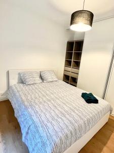 - une chambre avec un lit blanc et une couverture bleue dans l'établissement Deux pièces cosy à La Croisette, à Carrières-sous-Poissy