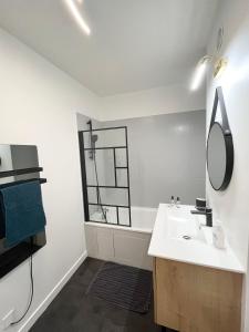 a white bathroom with a sink and a mirror at Deux pièces cosy à La Croisette in Carrières-sous-Poissy