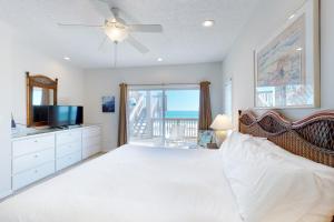 a bedroom with a bed with a ceiling fan and a television at Beach Boy in St. George Island