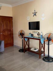 a living room with a tv and a table with two fans at Bongo Lodge in Las Galeras