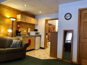 a kitchen with a couch and a clock on a wall at Susitna River Lodging, Suites in Talkeetna