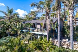 una casa con palmeras delante en Palms on Kennedy Point, en Te Whau Bay