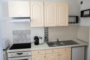 una cocina con armarios blancos y fregadero en Lorraine, en Mantes-la-Jolie