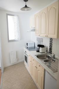 a kitchen with white cabinets and a sink at Lorraine in Mantes-la-Jolie