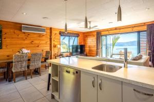 a kitchen with a sink and a living room at Palms on Kennedy Point in Te Whau Bay