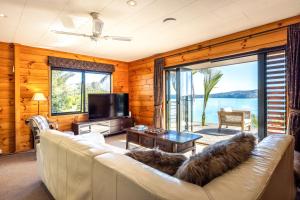 a living room with a couch and a large window at Palms on Kennedy Point in Te Whau Bay