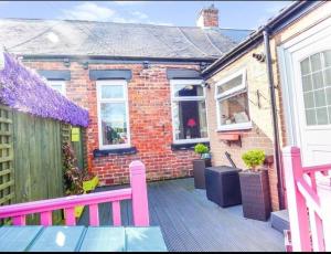 ein Backsteinhaus mit einer rosa Bank auf einer Terrasse in der Unterkunft Sommerset Cottages - 2 BR House in Sunderland