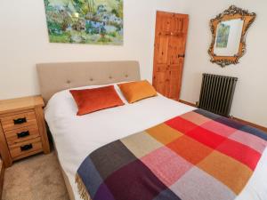 sypialnia z łóżkiem z kolorowym kocem i lustrem w obiekcie The Old Cobblers w mieście Hayfield
