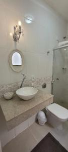 a bathroom with a sink and a toilet and a mirror at Sobrado 2 amplo e confortável em condomínio in Corumbá