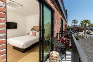 a room with a bed and a balcony with a bedroom at The Brick Boutique Hotel in Oceanside