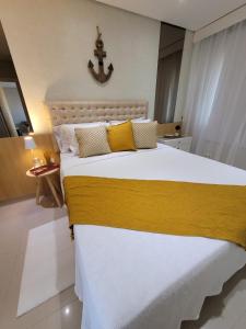 a bedroom with a large bed with yellow and white sheets at Casa Flórida in Aquiraz