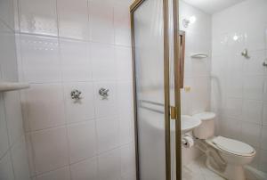 y baño blanco con aseo y ducha. en Hotel Toledo Plaza, en Armenia