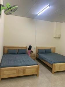 a little girl standing between two beds in a room at Gia lai Homestay Phương My in Pleiku